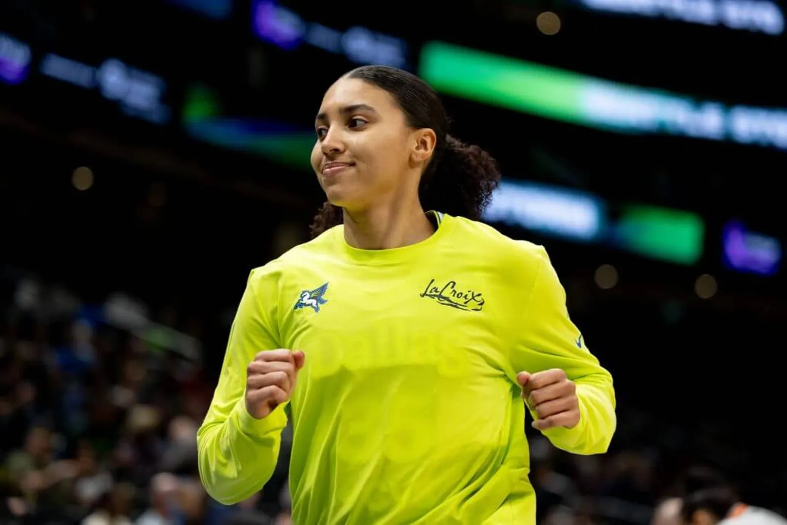 Azzi Fudd of the Dallas Wings holds up both of her hands while wearing a highlighter green warmup shirt.